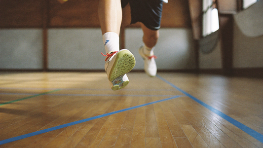 Nahaufnahme der Hallenschuhe eines Badmintonspielers im Sprung