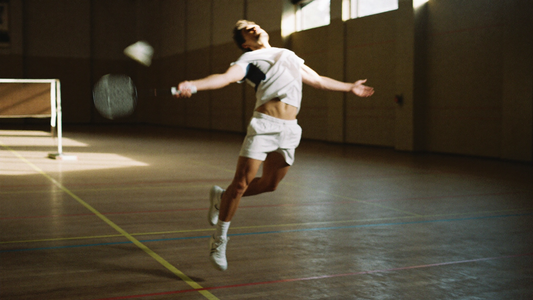 Badmintonspieler im Sprung-Smash in einer Sporthalle