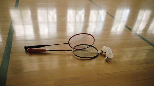 Zwei Badmintonschläger und Federbälle auf dem Hallenboden