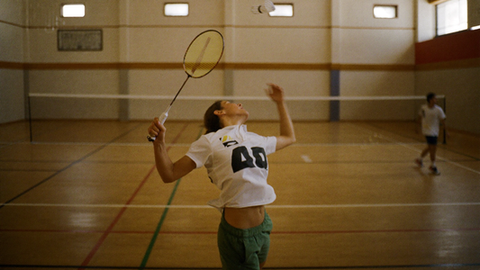 Badmintonspielerin beim Überkopfschlag mit Federball in der Luft