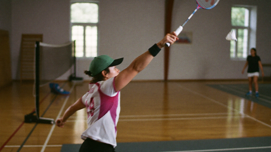 Badmintonspielerin streckt sich zum Schlag nach dem Federball in der Sporthalle